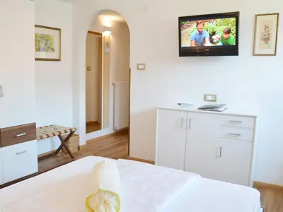 a bedroom with a bed and a tv on the wall at Hotel Karin in Tirolo