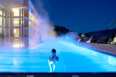 a person in a swimming pool at night at Hotel Cristallo - Wellness Mountain Living in La Villa