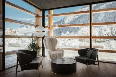 a living room with a view of snow covered mountains at Hotel Cristallo - Wellness Mountain Living in La Villa