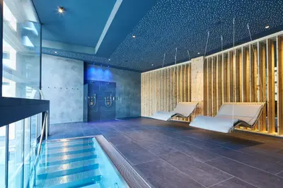 a pool room with two chairs and a table at Hotel Cristallo - Wellness Mountain Living in La Villa