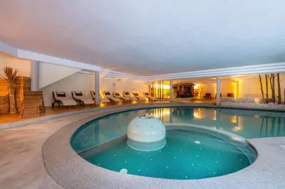 a large swimming pool in a hotel with chairs at Hotel Cristallo - Wellness Mountain Living in La Villa
