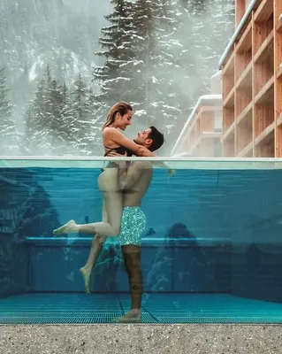 a man and a woman standing in a swimming pool at Hotel Cristallo - Wellness Mountain Living in La Villa