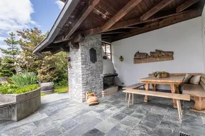 a patio with a wooden table and a stone fireplace at Chalet Luis in Falzes