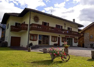 a building with a bench and flowers in front of it at La Casa del Mulino in Pozza di Fassa