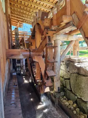 a large woodenmill in a building with a stone wall at La Casa del Mulino in Pozza di Fassa