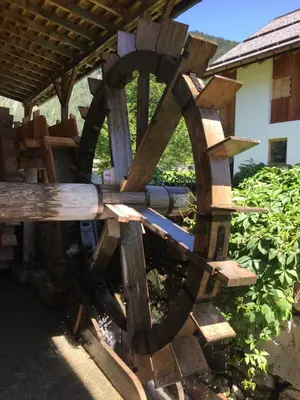 a woodenmill sitting in front of a building at La Casa del Mulino in Pozza di Fassa