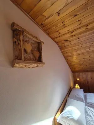 a bed in a room with a wooden ceiling at La Casa del Mulino in Pozza di Fassa