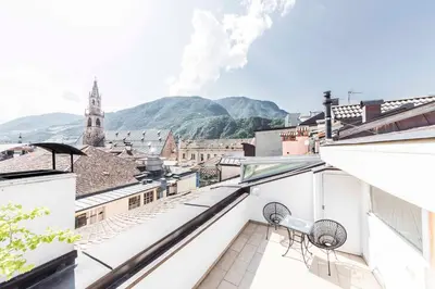 a view of a city from a balcony with mountains in the background at Stay COOPER l Goethe Suite in Bolzano