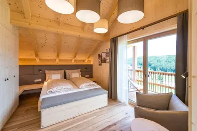 a bedroom with a bed and a large window at Mair am Graben Farm * Chalets in Terento