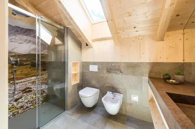 a bathroom with a toilet and a glass shower at Mair am Graben Farm * Chalets in Terento