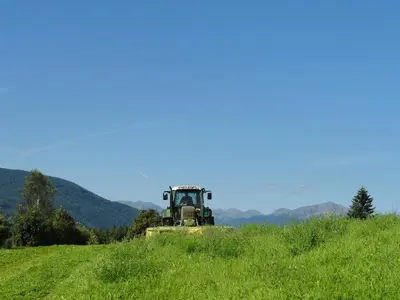 a tractor in a field of grass on a hill at Mair am Graben Farm * Chalets in Terento