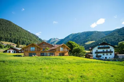 a house on a hill with mountains in the background at Mair am Graben Farm * Chalets in Terento