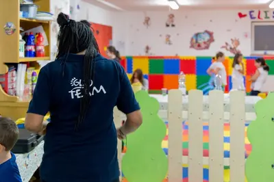 a woman standing in a play room with a fence at Family Hotel Andes - Only for Family in Vigo di Fassa