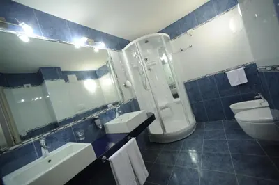 a blue tiled bathroom with a sink and a toilet at Family Hotel Andes - Only for Family in Vigo di Fassa
