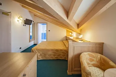 a bedroom with two beds and a desk in a room at Family Hotel Andes - Only for Family in Vigo di Fassa