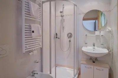 a white bathroom with a shower and a sink at Almarett in Racines