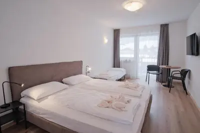a bedroom with a large bed with white sheets and chairs at Almarett in Racines