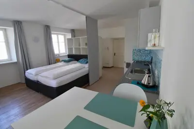 a bedroom with a bed and a kitchen with a table at Maria von Buol - Wohnen in Kaltern in Caldaro