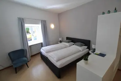 a bedroom with a bed and a blue chair at Maria von Buol - Wohnen in Kaltern in Caldaro