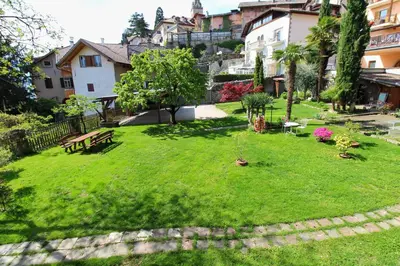 a green yard with a park bench and buildings at Maria von Buol - Wohnen in Kaltern in Caldaro