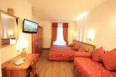 a hotel room with a bed and a couch at Hotel Trieste in Cortina dʼAmpezzo