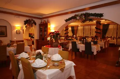 a restaurant with white tables and chairs and flowers at Hotel Trieste in Cortina dʼAmpezzo