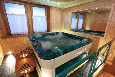 a large bath tub in a room with windows at Hotel Trieste in Cortina dʼAmpezzo