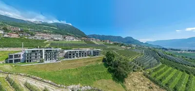 an aerial view of a vineyard with a building on a hill at Penthouse Skygarden in Schenna