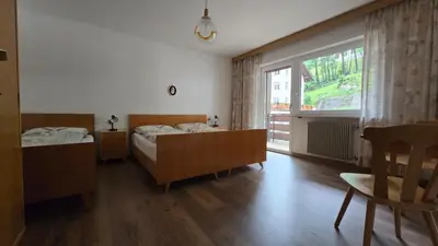 a bedroom with two beds and a large window at Appartamenti Bernard Sas in Canazei