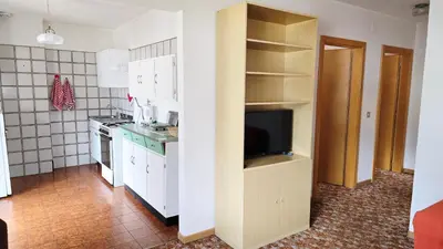 a kitchen with white cabinets and a flat screen tv at Appartamenti Bernard Sas in Canazei