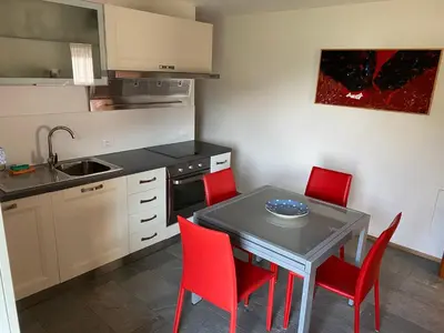 a kitchen with a table and four red chairs at Brentwaldhof Appartements in Cornedo all'Isarco