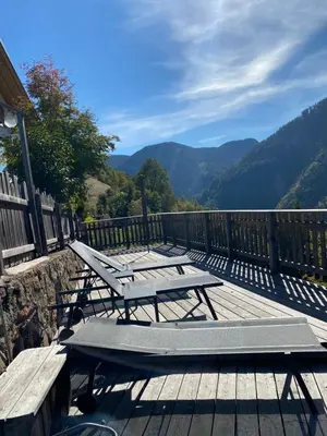a deck with picnic tables and a view of the mountains at Brentwaldhof Appartements in Cornedo all'Isarco