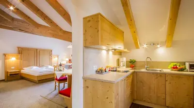 a kitchen with wooden cabinets and a bed in a room at Residence *** Geringerhof in Schenna