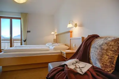 a hotel room with a bed and a chair at Residence *** Geringerhof in Schenna
