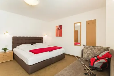 a bedroom with a large bed and a chair at Residence *** Geringerhof in Schenna