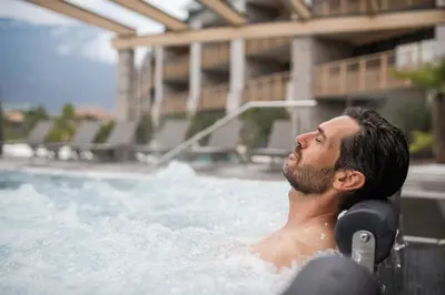 a man sitting in a swimming pool at Weinegg Wellviva Resort in Appiano sulla Strada del Vino