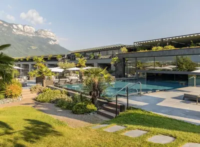 a resort with a pool and mountains in the background at Weinegg Wellviva Resort in Appiano sulla Strada del Vino