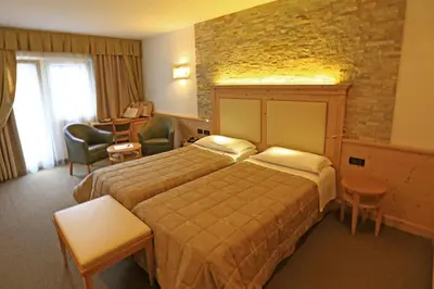 a hotel room with a bed and a desk at Hotel Ladina in Campitello di Fassa
