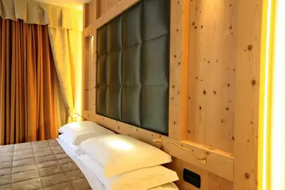 a room with a bed with a window and pillows at Hotel Ladina in Campitello di Fassa