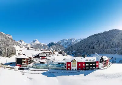 a village covered in snow with mountains in the background at Hotel Alpenroyal - The Leading Hotels of the World in Selva di Val Gardena