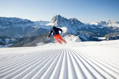 a person is skiing down a snow covered mountain at Hotel Alpenroyal - The Leading Hotels of the World in Selva di Val Gardena