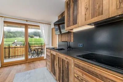 a kitchen with wooden cabinets and a view of a balcony at Ferienwohnung Mair am Bach in Brunico