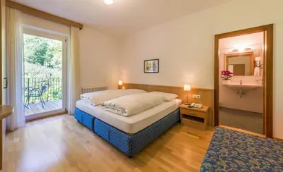 a bedroom with a bed and a bathroom with a window at Pension Gruenwald in Andrian
