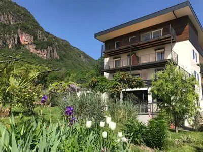 a building with a garden in front of a mountain at Pension Gruenwald in Andrian