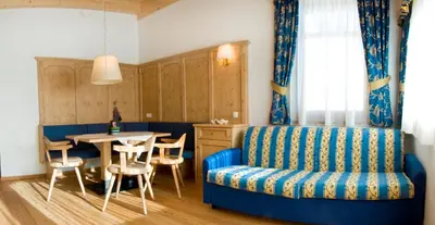 a living room with a blue couch and a table at Family and Wellness Residence Ciasa Antersies in San Cassiano