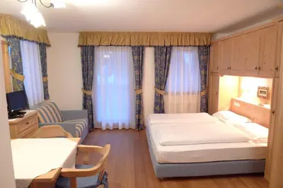 a bedroom with two beds and a chair and a desk at Family and Wellness Residence Ciasa Antersies in San Cassiano