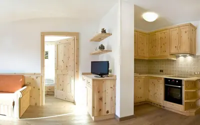 a kitchen with wooden cabinets and a tv on a counter at Family and Wellness Residence Ciasa Antersies in San Cassiano