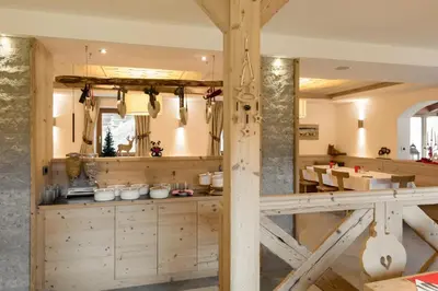 a kitchen with wooden cabinets and a dining room at Hotel Garni Lastei in Pozza di Fassa