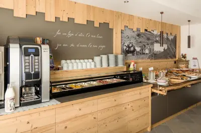 a restaurant with a counter with food on it at Hotel Garni Lastei in Pozza di Fassa