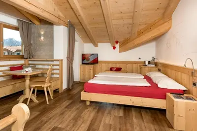 a bedroom with a large bed and a table at Hotel Garni Lastei in Pozza di Fassa